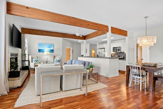 living room with beamed ceiling, ceiling fan with notable chandelier, and light hardwood / wood-style floors