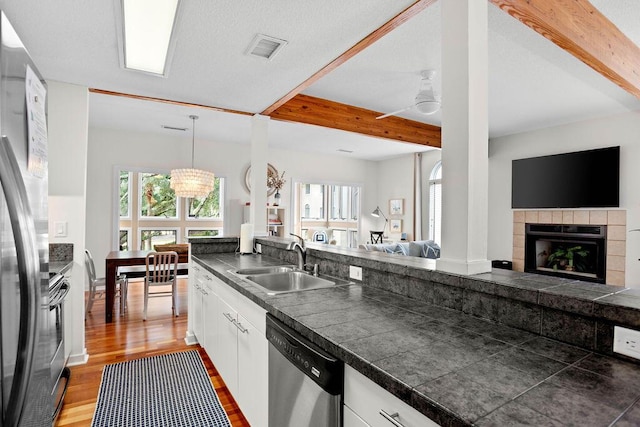 kitchen with a fireplace, stainless steel appliances, white cabinetry, and sink