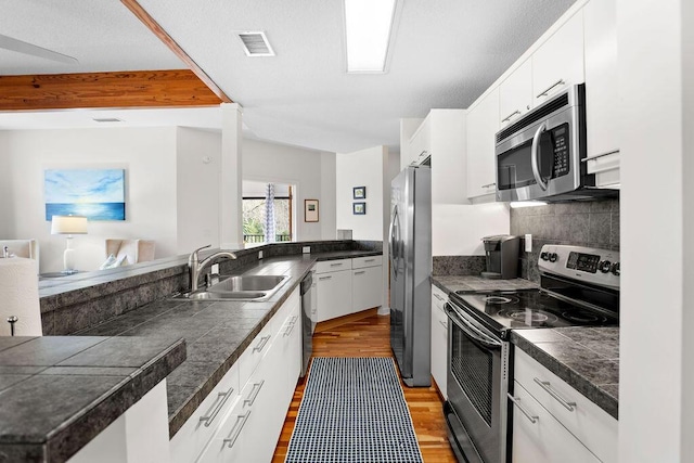 kitchen with white cabinets, sink, light wood-type flooring, kitchen peninsula, and stainless steel appliances