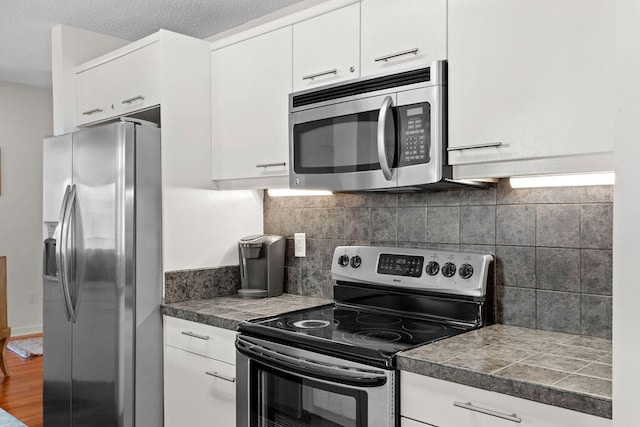 kitchen featuring appliances with stainless steel finishes, backsplash, a textured ceiling, and white cabinetry