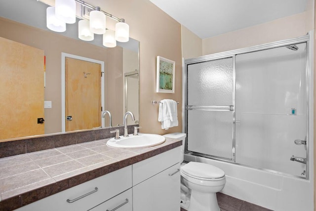 full bathroom featuring vanity, toilet, and bath / shower combo with glass door