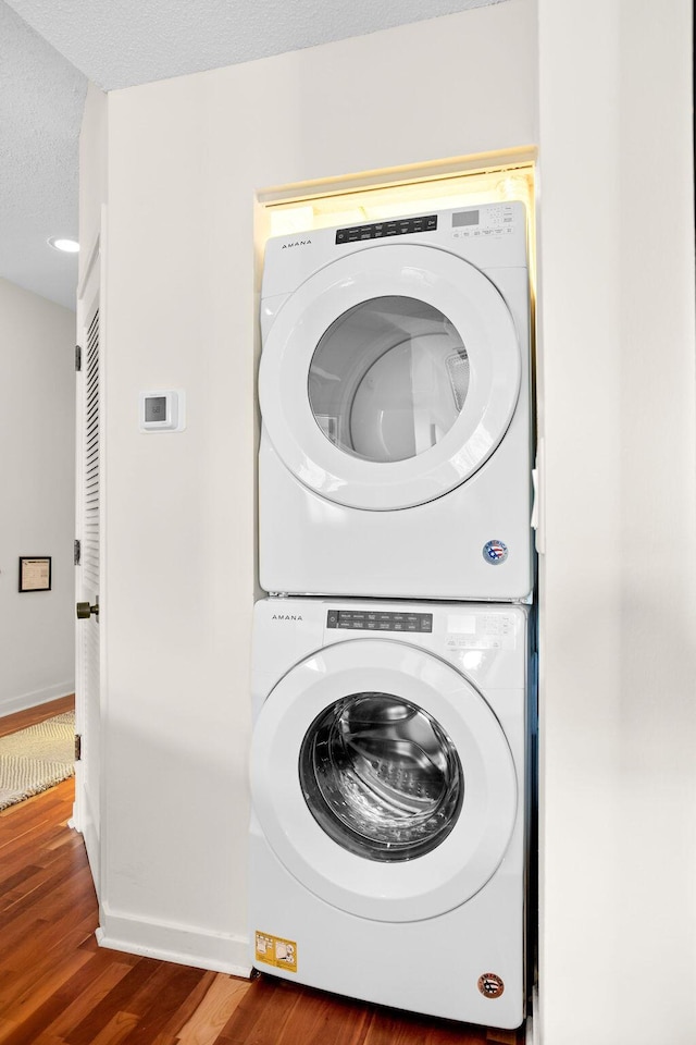 washroom with stacked washer / dryer, dark hardwood / wood-style flooring, and a textured ceiling