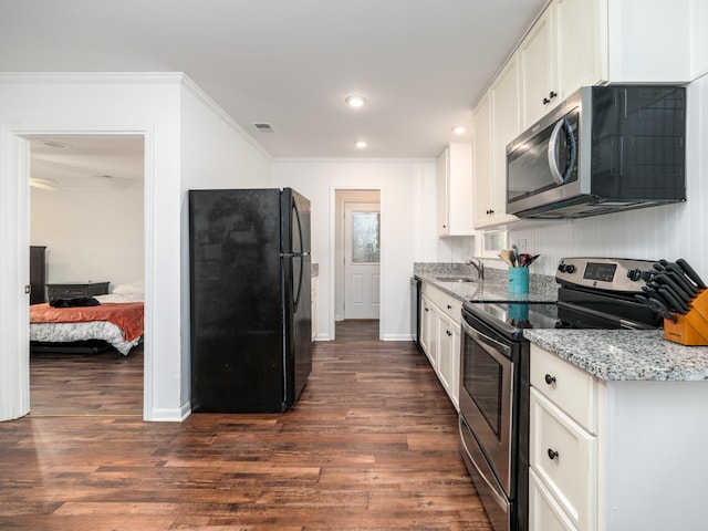 kitchen with light stone counters, white cabinets, sink, dark wood-type flooring, and appliances with stainless steel finishes