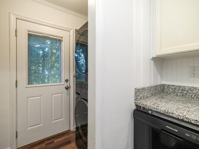 clothes washing area with ornamental molding, stacked washer and dryer, and dark wood-type flooring