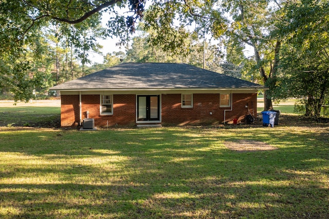 rear view of property with cooling unit and a yard