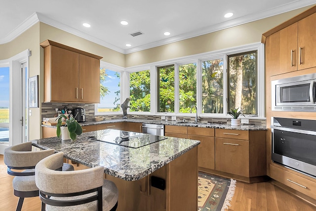 kitchen featuring stainless steel appliances, sink, a breakfast bar area, and dark stone counters