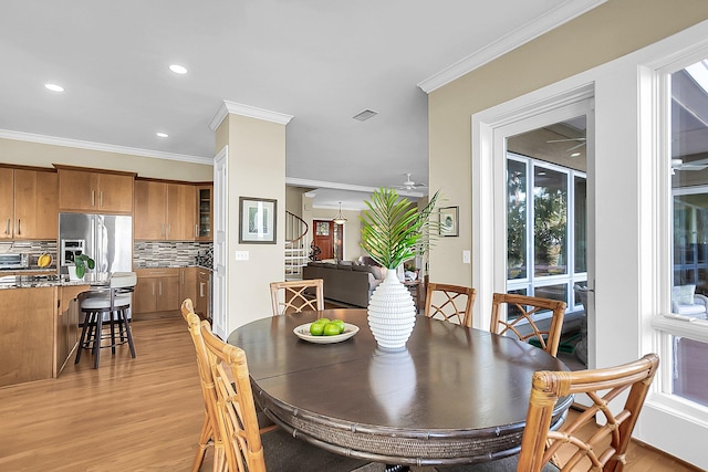 dining room with ornamental molding and light hardwood / wood-style flooring