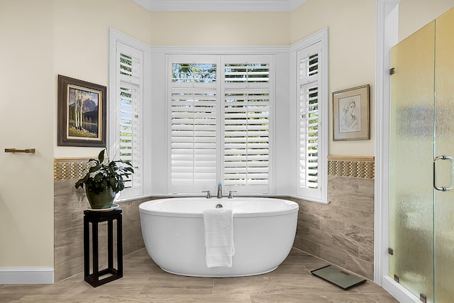 bathroom with a healthy amount of sunlight, separate shower and tub, and tile walls