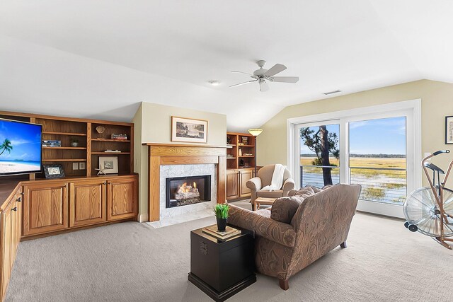 carpeted living room featuring a premium fireplace, vaulted ceiling, and ceiling fan