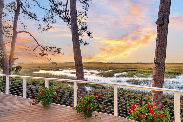 deck at dusk featuring a water view and a rural view