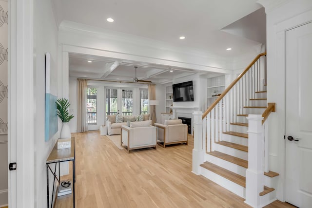 living room featuring a fireplace, coffered ceiling, stairs, light wood-type flooring, and beam ceiling