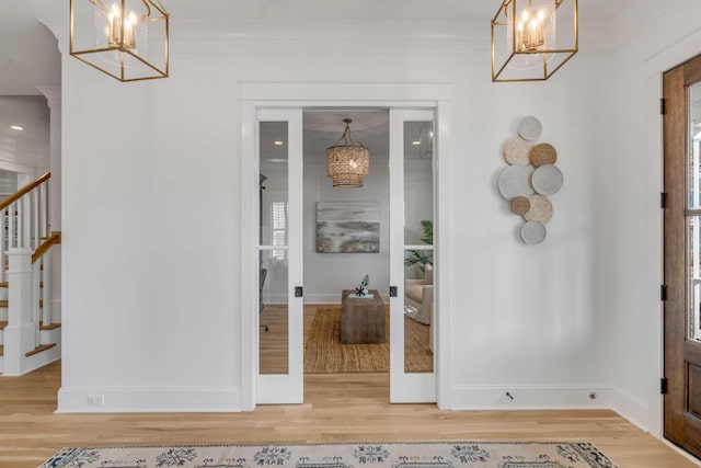 foyer featuring a chandelier, ornamental molding, and light wood finished floors