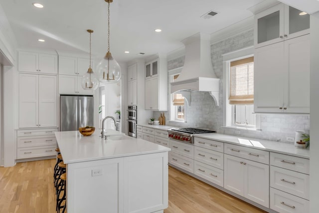 kitchen featuring a breakfast bar, stainless steel appliances, crown molding, premium range hood, and a sink