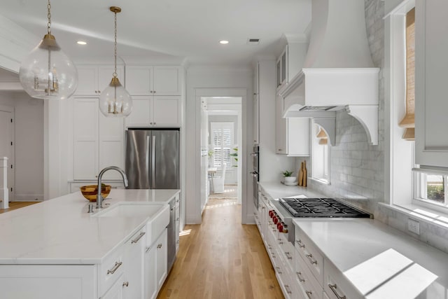 kitchen with stainless steel appliances, a sink, white cabinetry, light wood-type flooring, and decorative backsplash