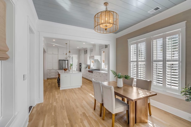 dining area with a chandelier, light wood-type flooring, a wealth of natural light, and baseboards