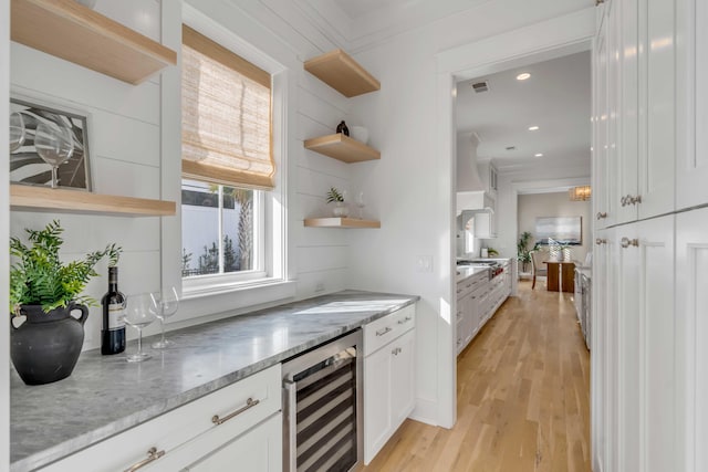 kitchen featuring white cabinets, wine cooler, light stone countertops, light wood-type flooring, and open shelves