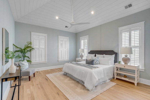 bedroom with light wood-style flooring, multiple windows, visible vents, and baseboards