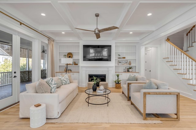 living area with stairs, coffered ceiling, and wood finished floors