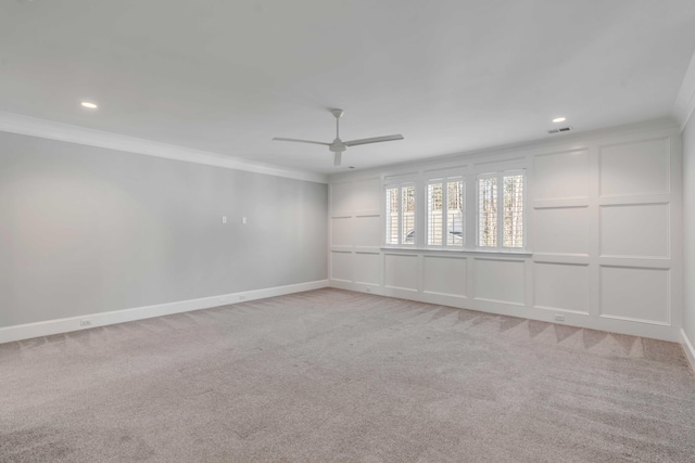 empty room with visible vents, a ceiling fan, light colored carpet, ornamental molding, and a decorative wall