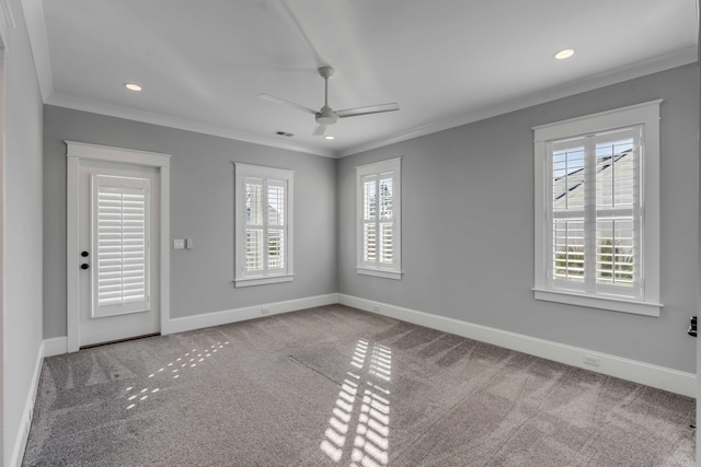 unfurnished room with carpet, visible vents, ornamental molding, a ceiling fan, and baseboards