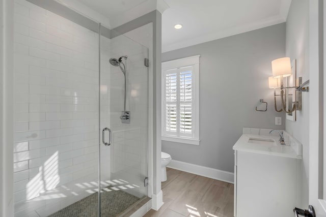 bathroom with toilet, vanity, baseboards, a stall shower, and crown molding