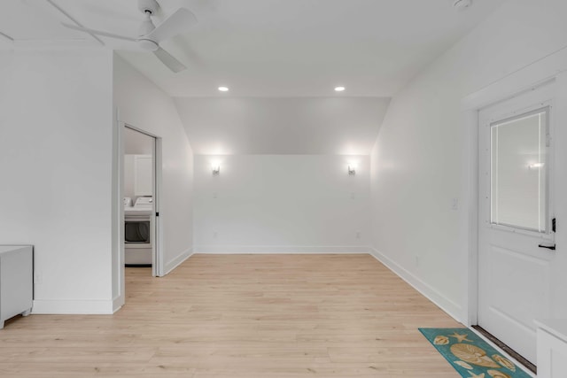 empty room with ceiling fan, light wood-style flooring, baseboards, vaulted ceiling, and washer / dryer