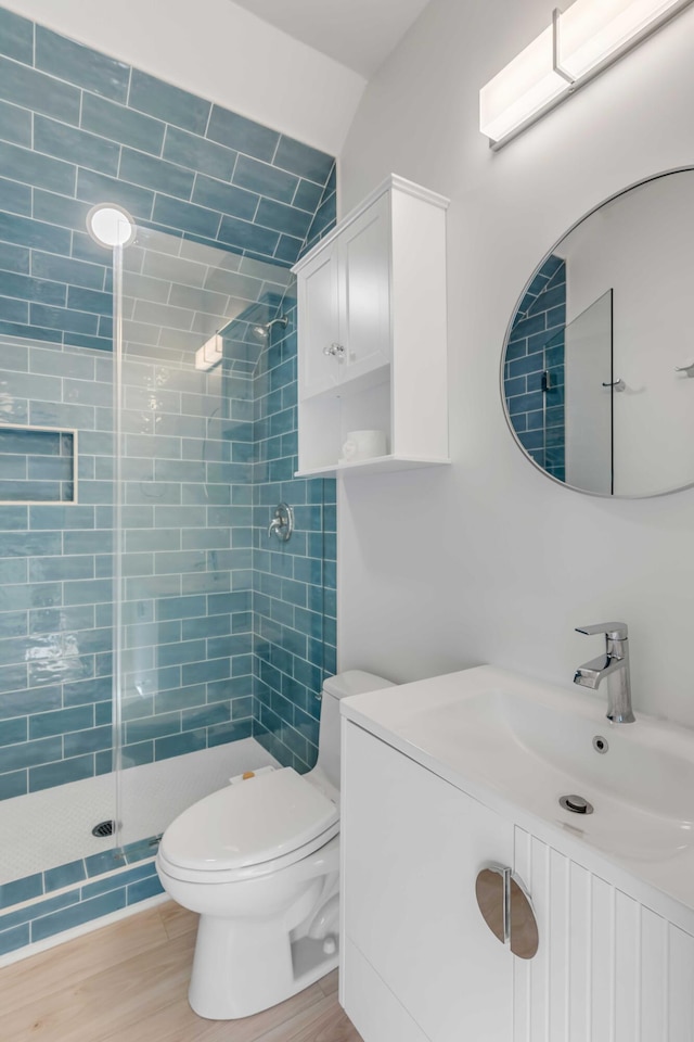 bathroom featuring toilet, a stall shower, wood finished floors, and vanity