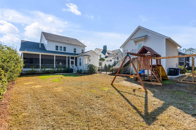 back of house featuring a yard, a playground, fence, and a sunroom