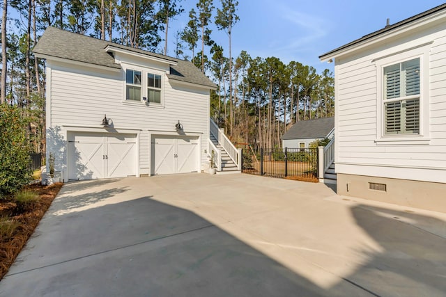 view of home's exterior with an attached garage, fence, concrete driveway, stairway, and crawl space