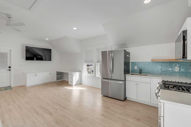 kitchen featuring light wood-style flooring, a sink, stainless steel appliances, light countertops, and backsplash