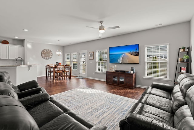 living room featuring ceiling fan, sink, and dark hardwood / wood-style flooring