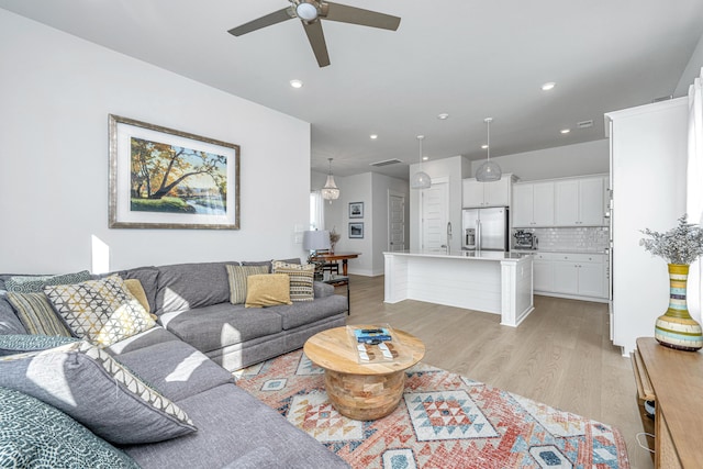 living room with ceiling fan, sink, and light hardwood / wood-style floors