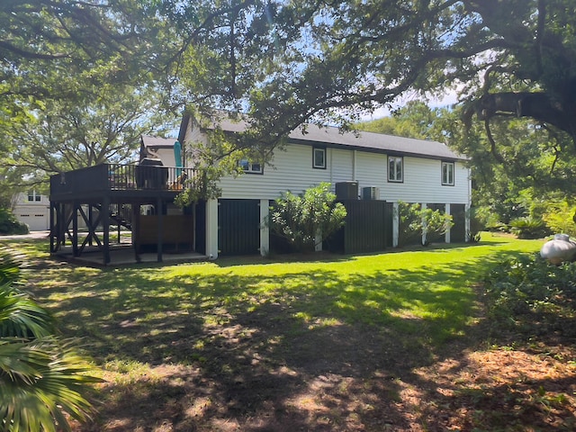 rear view of house with central AC unit, a wooden deck, and a lawn