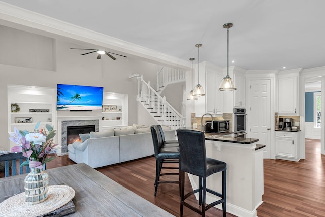2720 Oak Manor Dr, Mount Pleasant, SC 29466 - kitchen with dark countertops, a kitchen bar, appliances with stainless steel finishes, white cabinets, and dark wood finished floors