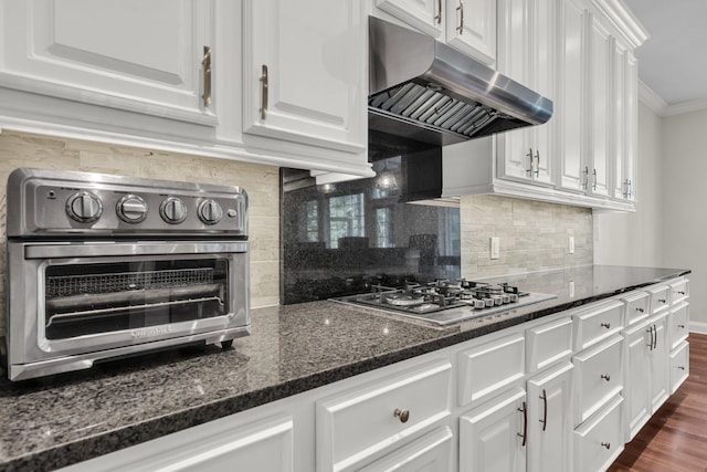 2720 Oak Manor Dr, Mount Pleasant, SC 29466 - kitchen with under cabinet range hood, white cabinets, decorative backsplash, dark stone counters, and crown molding