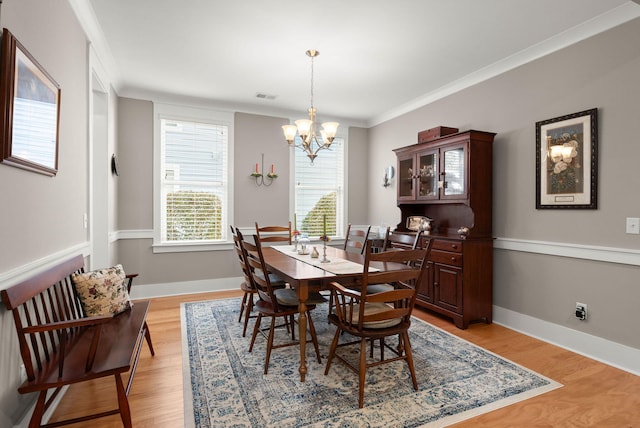 dining area with a notable chandelier, crown molding, and light hardwood / wood-style floors