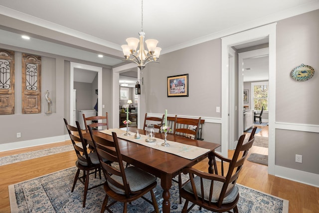 dining room with ornamental molding, light hardwood / wood-style floors, and an inviting chandelier