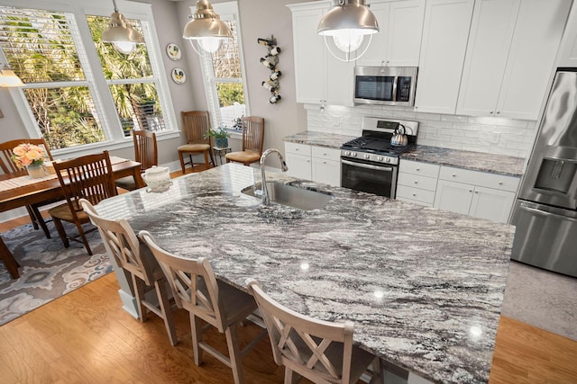 kitchen with sink, white cabinetry, appliances with stainless steel finishes, and dark stone countertops