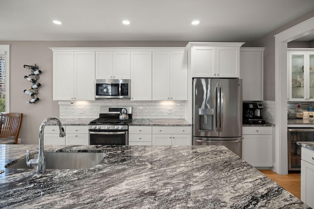 kitchen featuring sink, white cabinetry, dark stone counters, and appliances with stainless steel finishes