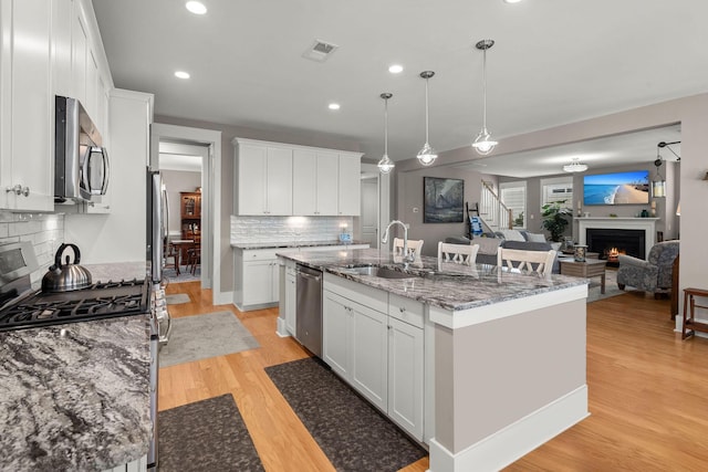 kitchen featuring sink, appliances with stainless steel finishes, white cabinetry, and an island with sink