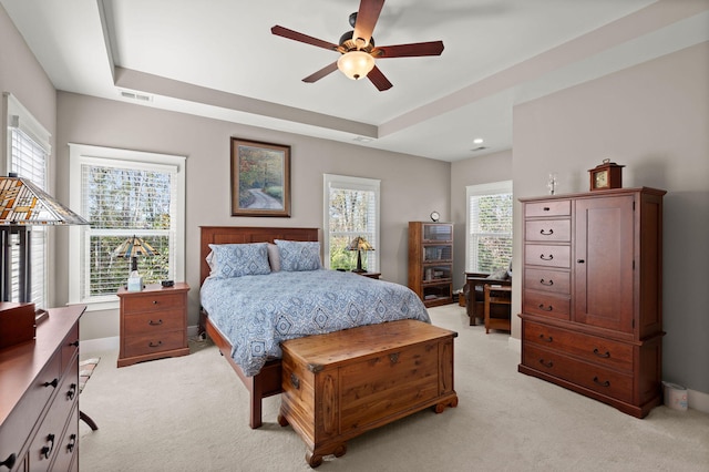 bedroom featuring light colored carpet, ceiling fan, and a raised ceiling