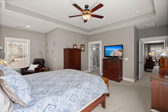 bedroom featuring ceiling fan, a raised ceiling, and light colored carpet