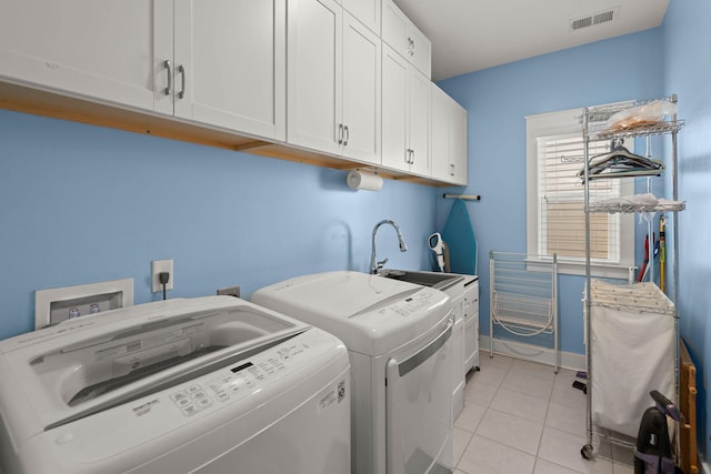 clothes washing area featuring sink, cabinets, light tile patterned floors, and separate washer and dryer