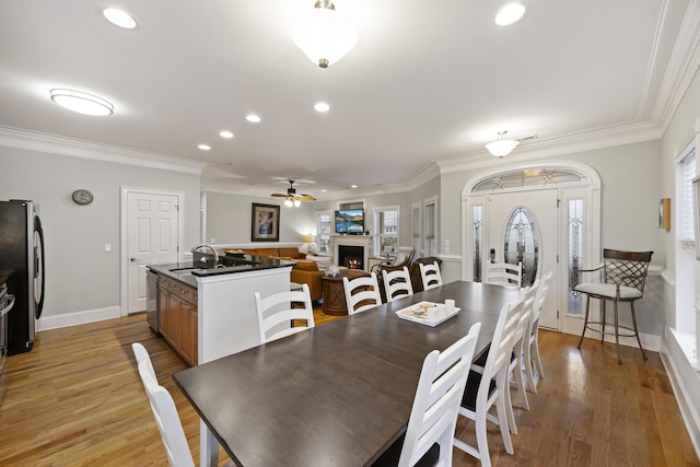 dining area with sink, ornamental molding, and light hardwood / wood-style floors