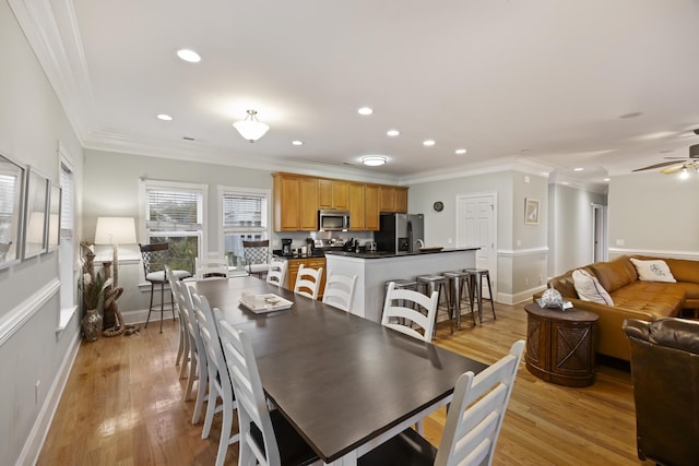 dining area featuring light hardwood / wood-style flooring, ornamental molding, and ceiling fan