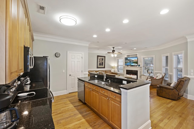 kitchen with appliances with stainless steel finishes, sink, dark stone countertops, a kitchen island with sink, and crown molding