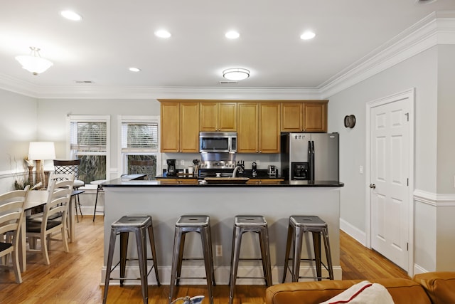 kitchen featuring ornamental molding, appliances with stainless steel finishes, and a kitchen breakfast bar