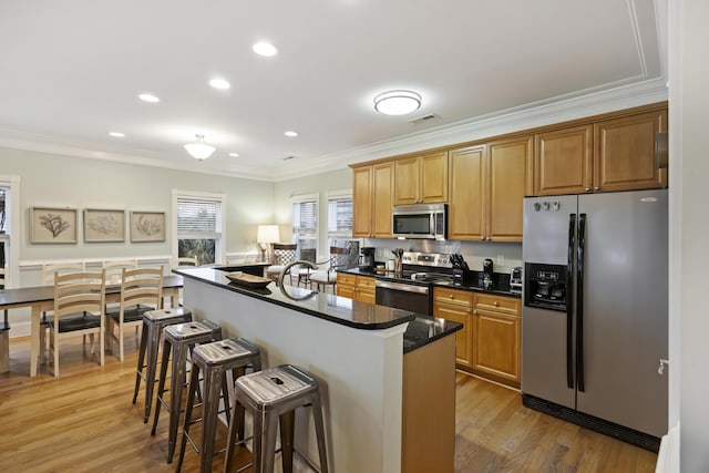 kitchen featuring ornamental molding, appliances with stainless steel finishes, hardwood / wood-style floors, and a kitchen island