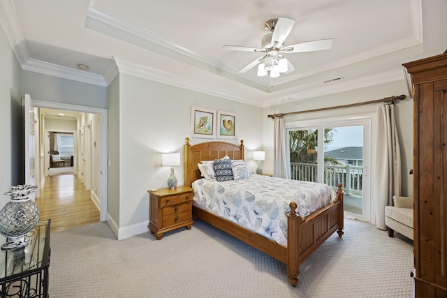 carpeted bedroom with crown molding, ceiling fan, a tray ceiling, and access to exterior