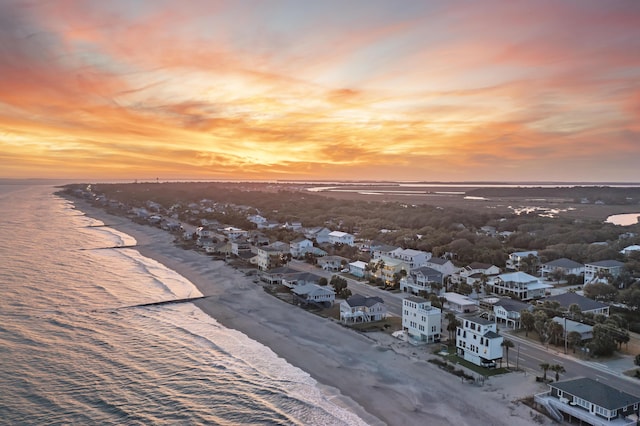 aerial view at dusk with a water view and a view of the beach